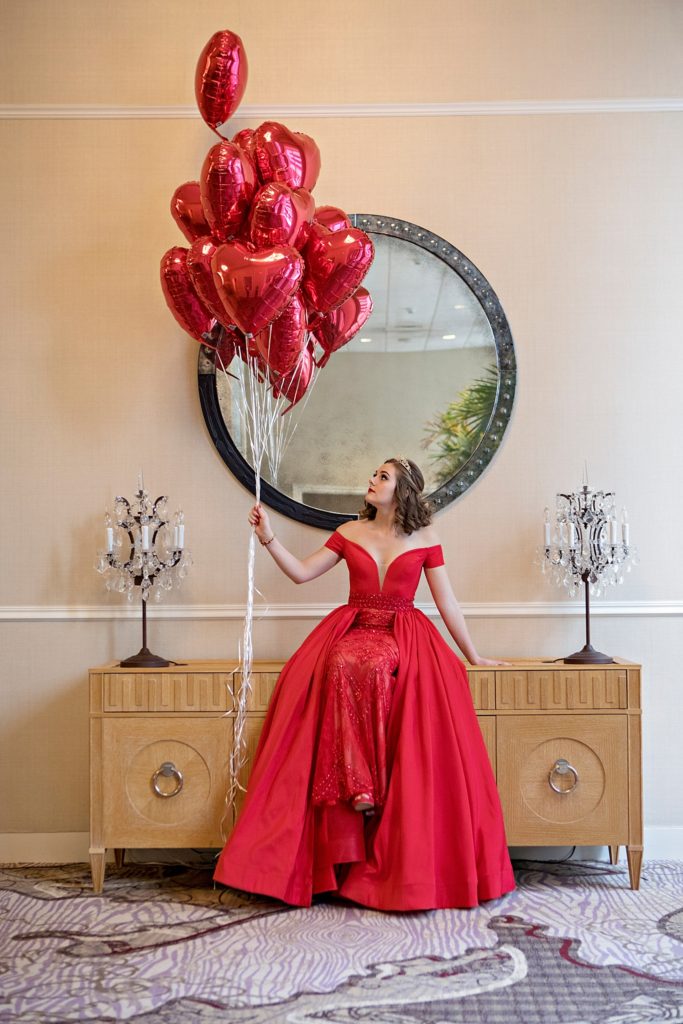 red prom dress holding heart balloons