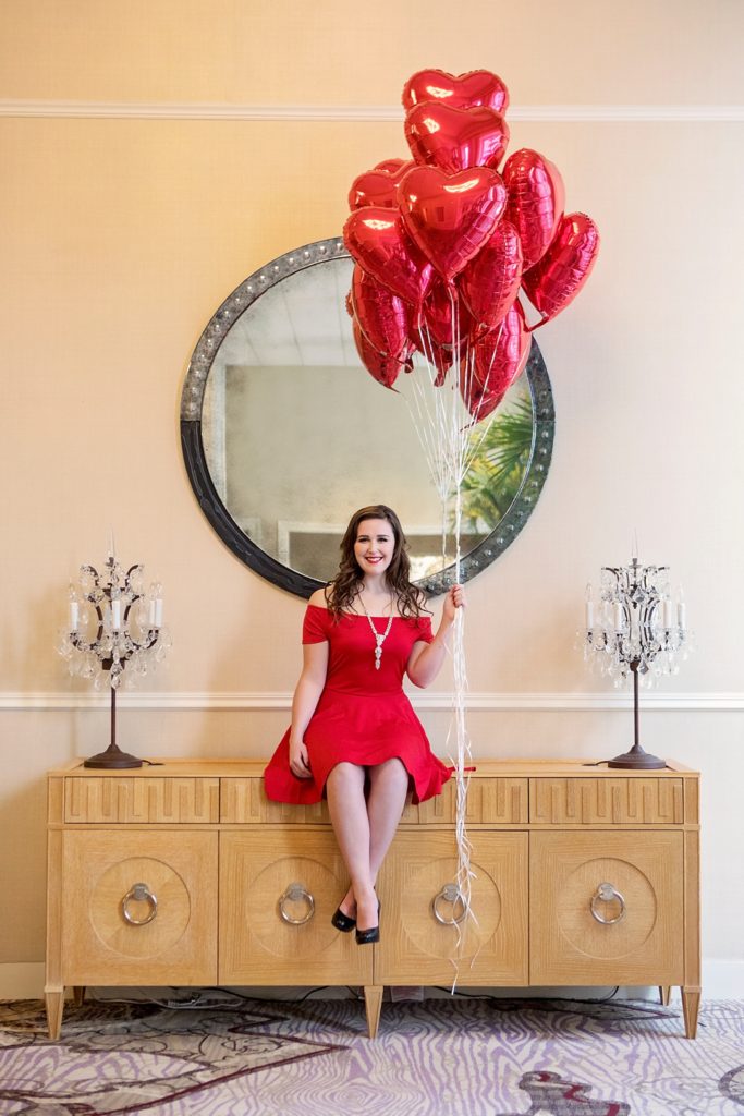 senior in red dress holding heart balloons
