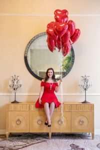 senior in red dress holding heart balloons